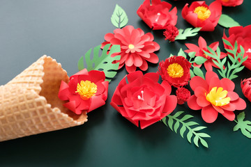 Waffle cone with paper flowers on dark background. Holiday concept.