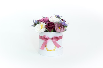 Flowers in bloom: multi-colored red and pink buds in a white round box on a white background.