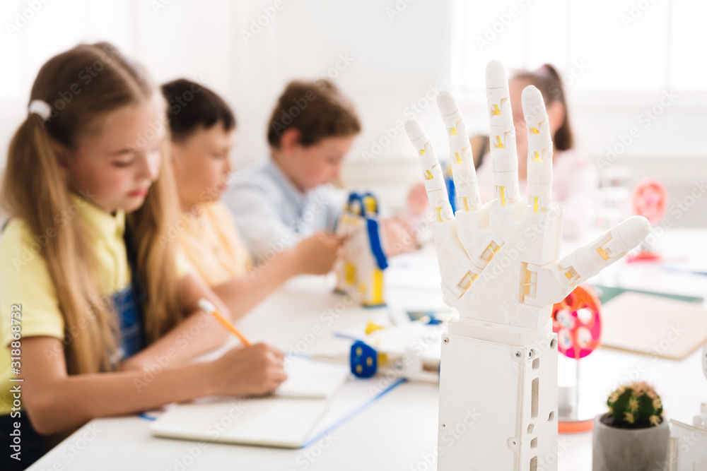 Poster children learning in class with humanoid robotic hand on foreground