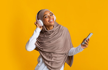 Afro Muslim Girl Listening Music On Smartphone With Wireless Headphones