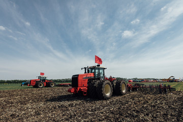 red tractor with big wheels in the field against the blue sky