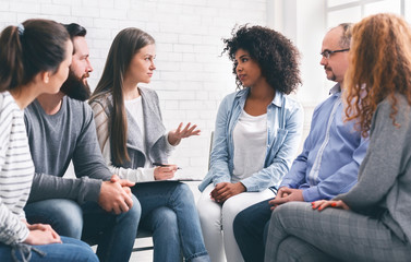 Diverce people talking with professional therapist at group meeting