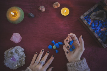 Young woman catching and observing precious stones with a mystical background of crystals and candles