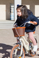 Little Smiling girl riding the bike in the city.