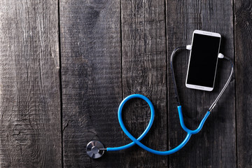 Smartphone and stethoscope on wooden rustic background