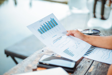 Businessman hold paper graph chart on the table near the river. Working at vocation.