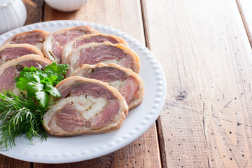 Cooked pork knuckle roll with chicken on a white plate, horizontal, copy space