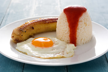 Arroz a la cubana Typical Cuban rice with fried banana and fried egg on blue wooden table.	