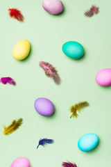 Easter colorful flat lay pattern with eggs and feather