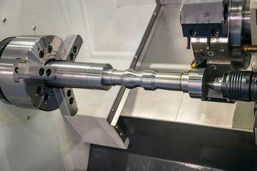 The CNC lathe machine in metal working process cutting the metal shaft parts with in the light blue...