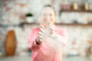 Close up of woman clapping hands and splashing flour. Woman in kitchen.