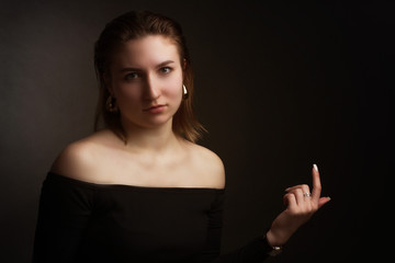 Portrait in the photo Studio of brown-haired girl, on a black background in black clothes with open shoulders. Short hair.