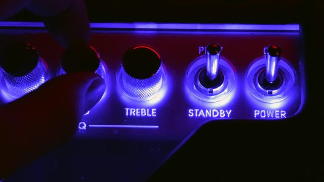 Close up of Hand Adjusting EQ on Guitar Amplifier 