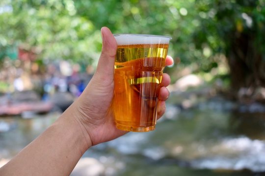 Cropped Image Of Hand Holding Beer Glass Outdoors
