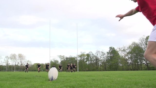 Scoring a conversion with a Rugby Kick. A player is kicking the ball during a match through the rugby posts. Super Slow motion. Wide