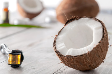 Coconut halved, essential oil in a glass bottle, cream and facial massager on a gray wooden table. Personal care. Spa treatments. Cosmetology. Natural and organic cosmetics.