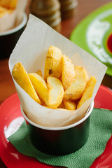 Fried potatoes rolled in parchment over a table.
