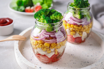 Healthy salad in glass jars on light table