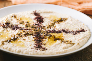 Home made hummus plate , decorated with boiled , herbs, and olive oil on dark background