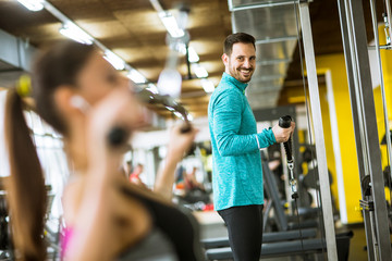 Young couple exercise bodybuilding exercises in the modern gym