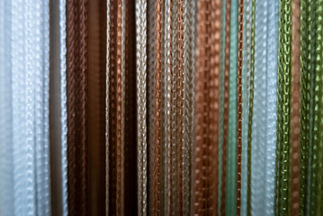 Textile strings and ropes hangs in a fabric shop. Abstract background.