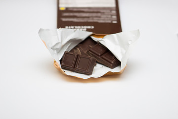 Dark chocolate in an open package on a close-up on a white background. Free space for text