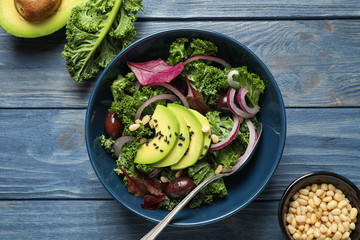 Tasty fresh kale salad on blue wooden table, flat lay