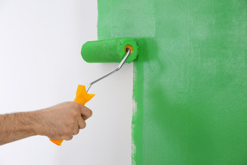 Man painting white wall with green dye, closeup. Interior renovation