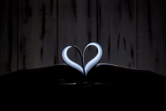 A heart from book pages shines in the dark. - Powered by Adobe