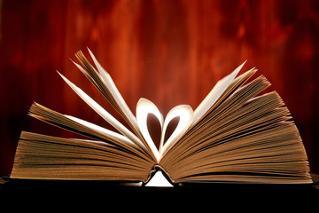 A heart from book pages shines in on a brown background.