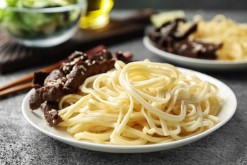 Tasty cooked rice noodles with meat on grey table
