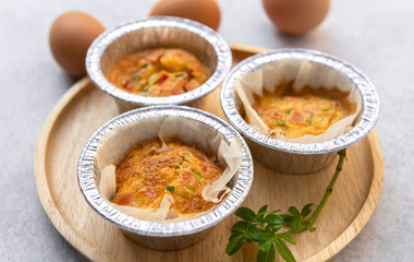 Close-up eggs omelette food with foil tray on bamboo wooden plate decoration with green plant.