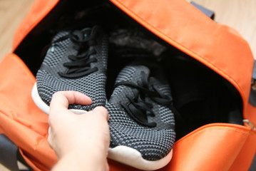 puts sneakers in a sports bag, preparing things for training