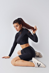 Fototapeta premium Twerk dancing. Sportive woman in black clothes in the studio against white background