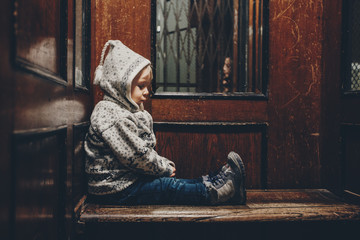 Sweet toddler blonde boy, sitting in an old wooden elevator or lift © Tomsickova