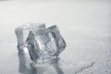 Crystal clear ice cubes with water drops on grey table, closeup. Space for text