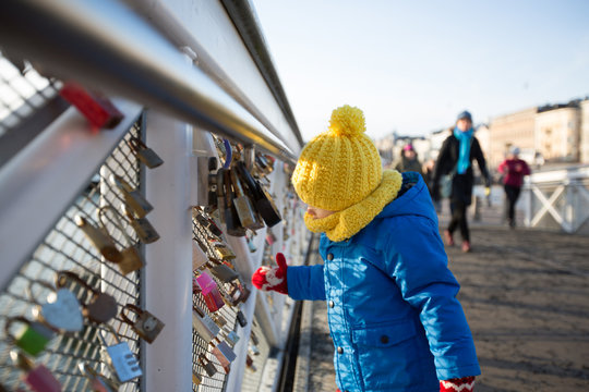 Cute toddler child, looking at love locks, locked on a bridge fence