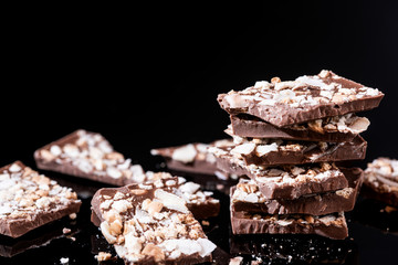 Stack of Broken Chocolate Pieces on Black Background. Copy Space. Closeup View