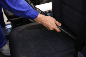 Car wash worker vacuuming automobile seat, closeup