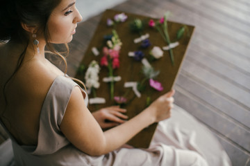 A girl in a Pink Dress Looks at Fresh Flowers on a Board