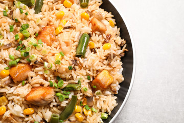 Delicious rice pilaf with chicken and vegetables on light grey table, closeup