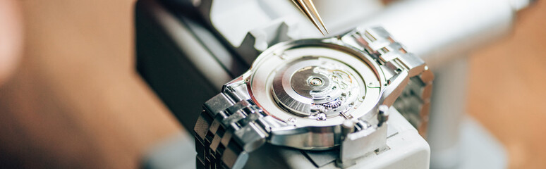Panoramic shot of wristwatch on watch tester by tweezers on table - obrazy, fototapety, plakaty