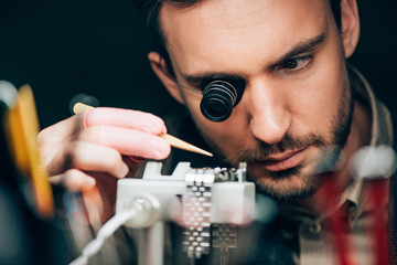 Selective focus of watchmaker working with wristwatch on timegrapher movement holder isolated on...