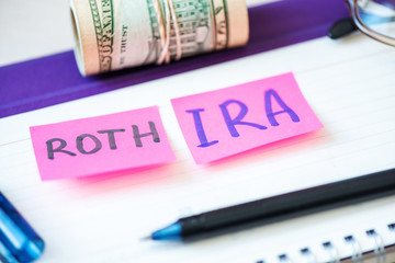401k ira roth on pieces of colorful paper dollars on table. Pension concept. Retirement plans.