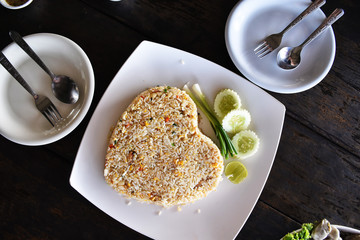 Crab Fried Rice heart shape on white dish with cucumber and onion, put on a plate.