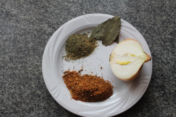 A plate with seasonings on a granite table