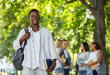 Happy afro student with books smiling at camera