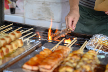 Traditional some meat skewers being grilled in a barbecue, in Japan at street food vendor market, grilled satay. Japanese Food.
