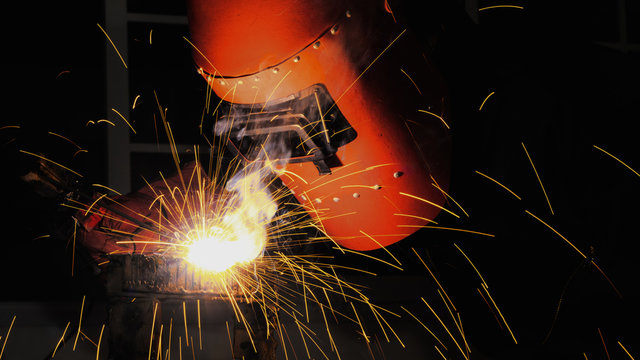 worker with protective mask welding metal