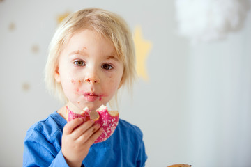 Cute sweet blonde child, playing and eating donuts